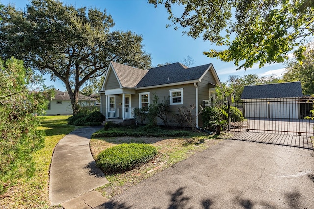 view of front of house with a porch, a garage, an outbuilding, and a front yard