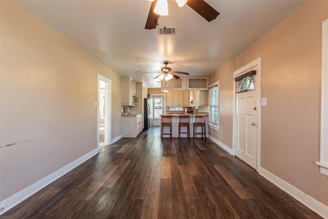 kitchen featuring a center island, a kitchen bar, refrigerator, ceiling fan, and dark hardwood / wood-style flooring