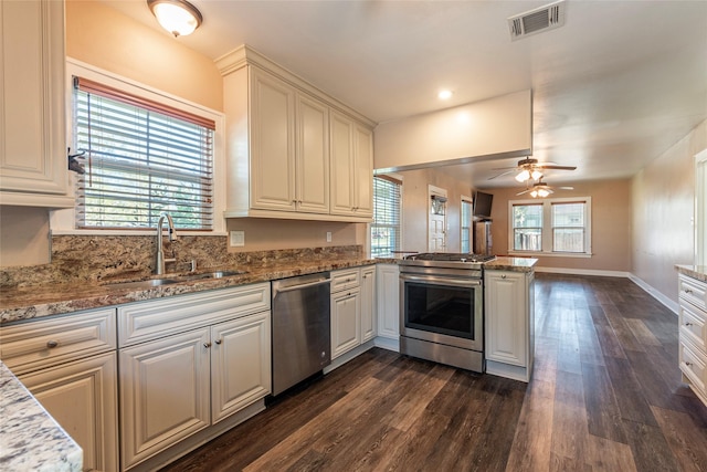 kitchen with a wealth of natural light, kitchen peninsula, sink, and appliances with stainless steel finishes