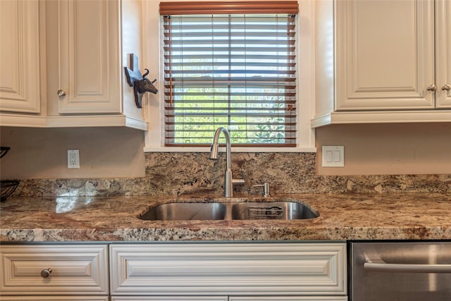 kitchen featuring stone counters, sink, white cabinets, and stainless steel dishwasher