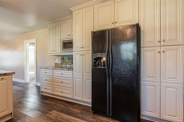 kitchen featuring dark hardwood / wood-style flooring, black fridge, stainless steel microwave, and light stone counters