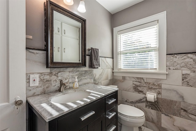 bathroom featuring vanity, tile walls, and toilet