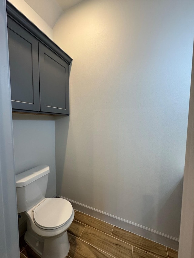 bathroom featuring toilet, baseboards, and wood finish floors