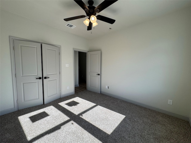 unfurnished bedroom with dark colored carpet, a closet, and ceiling fan