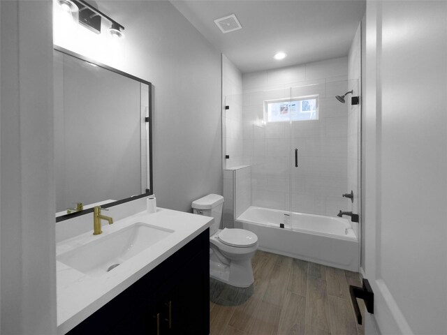 full bathroom featuring vanity, wood-type flooring, tiled shower / bath combo, and toilet