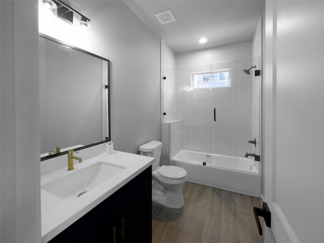 bathroom featuring visible vents, toilet, vanity, shower / tub combination, and wood finished floors