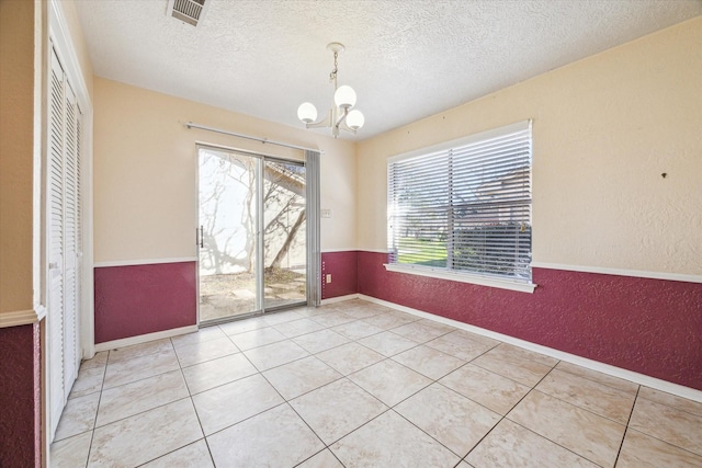 unfurnished dining area with light tile patterned floors, a textured ceiling, and a notable chandelier