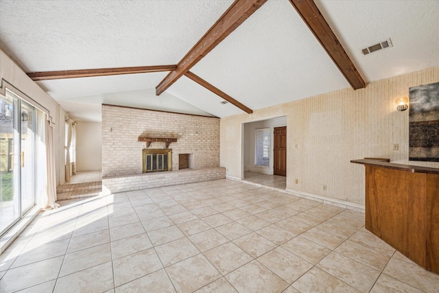 unfurnished living room with a textured ceiling, lofted ceiling with beams, a brick fireplace, and light tile patterned flooring