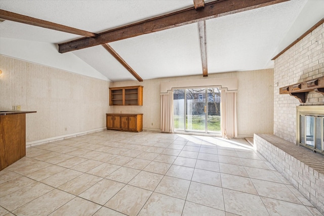 unfurnished living room with vaulted ceiling with beams, light tile patterned floors, a textured ceiling, and a brick fireplace