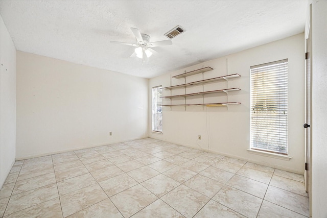 tiled empty room featuring ceiling fan and a textured ceiling