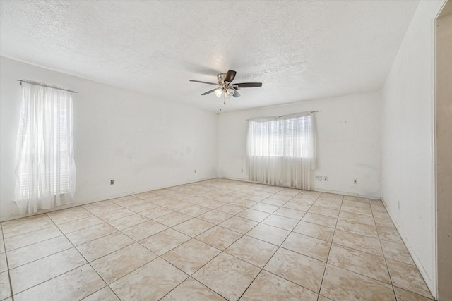 tiled empty room featuring ceiling fan, plenty of natural light, and a textured ceiling