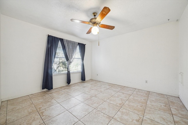 empty room featuring ceiling fan, light tile patterned floors, and a textured ceiling