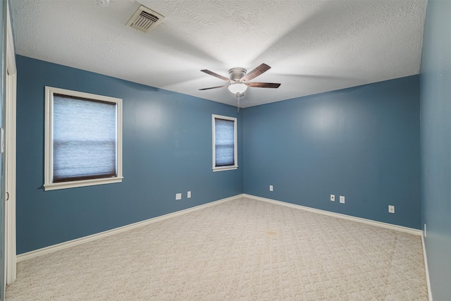 carpeted spare room featuring plenty of natural light, ceiling fan, and a textured ceiling