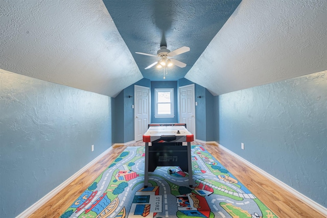 rec room with a textured ceiling, hardwood / wood-style flooring, ceiling fan, and lofted ceiling