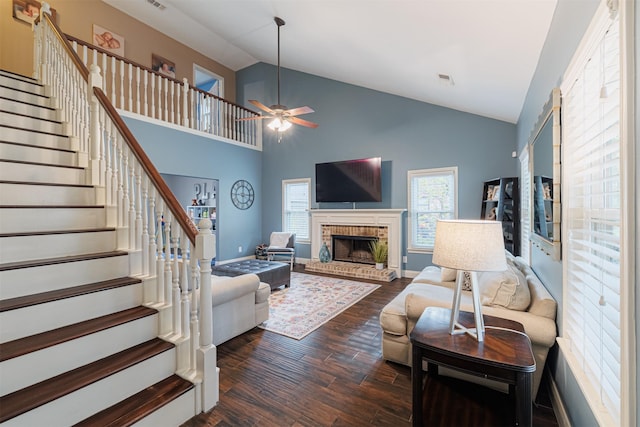 living room with a fireplace, high vaulted ceiling, ceiling fan, and dark wood-type flooring