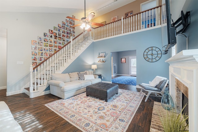 living room with ceiling fan, high vaulted ceiling, dark wood-type flooring, and a brick fireplace