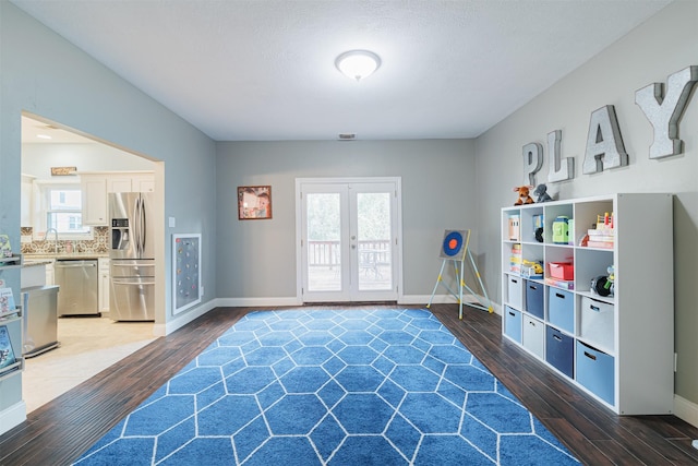 game room featuring dark hardwood / wood-style flooring, a healthy amount of sunlight, and french doors