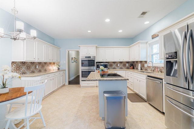 kitchen with pendant lighting, a center island, sink, white cabinetry, and stainless steel appliances