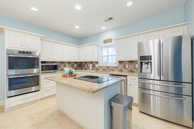 kitchen featuring white cabinets, a kitchen island, sink, and appliances with stainless steel finishes