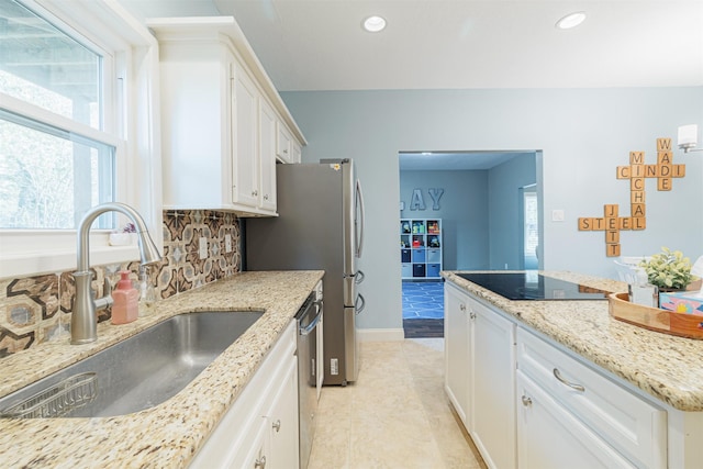 kitchen featuring sink, light stone counters, stainless steel dishwasher, black electric cooktop, and white cabinets