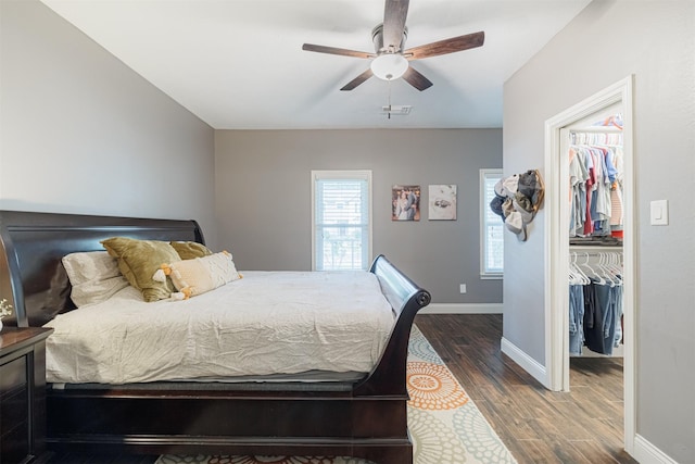 bedroom with ceiling fan, a spacious closet, dark wood-type flooring, and a closet