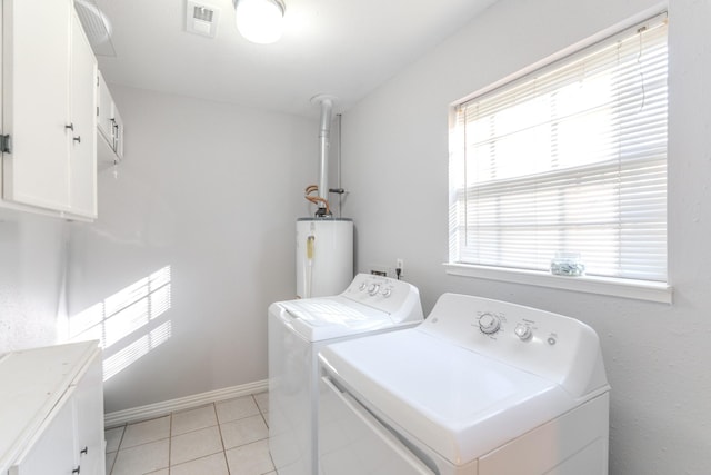 clothes washing area featuring water heater, washer and clothes dryer, light tile patterned flooring, and cabinets