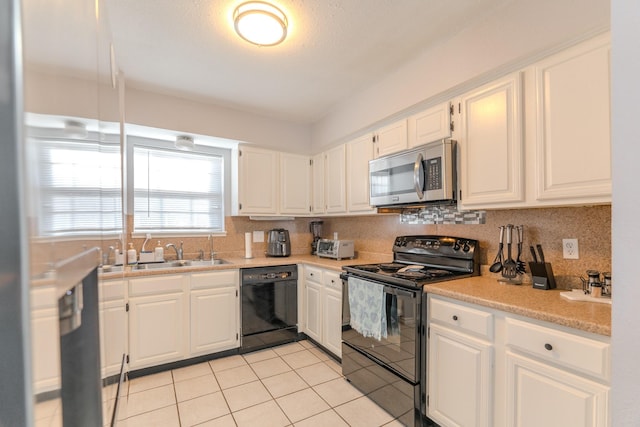 kitchen with backsplash, black appliances, sink, light tile patterned flooring, and white cabinetry