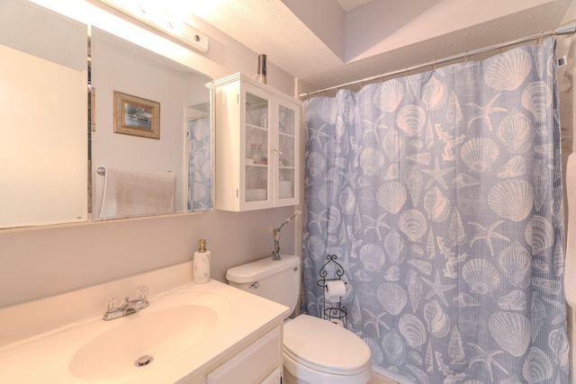 bathroom with a textured ceiling, vanity, and toilet