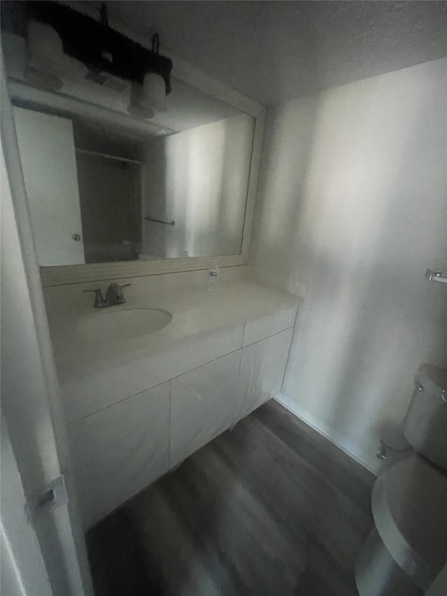 bathroom with toilet, vanity, and hardwood / wood-style flooring