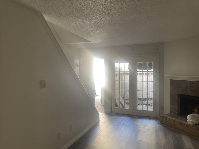 unfurnished living room featuring a fireplace, hardwood / wood-style floors, and a textured ceiling