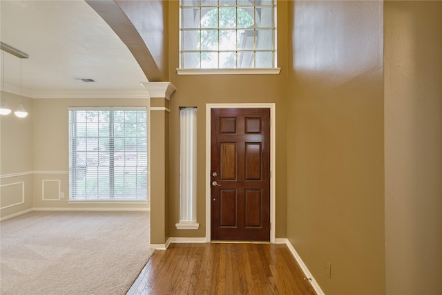 foyer entrance with wood-type flooring, ornate columns, and crown molding