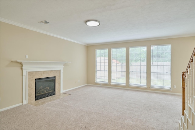 unfurnished living room with a tiled fireplace, light carpet, and crown molding