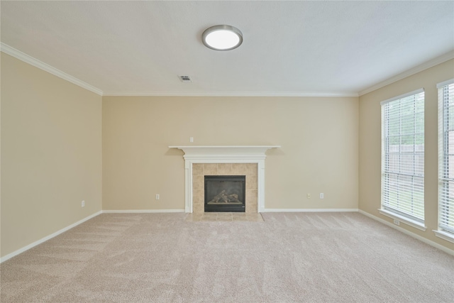 unfurnished living room with light carpet, plenty of natural light, ornamental molding, and a tiled fireplace