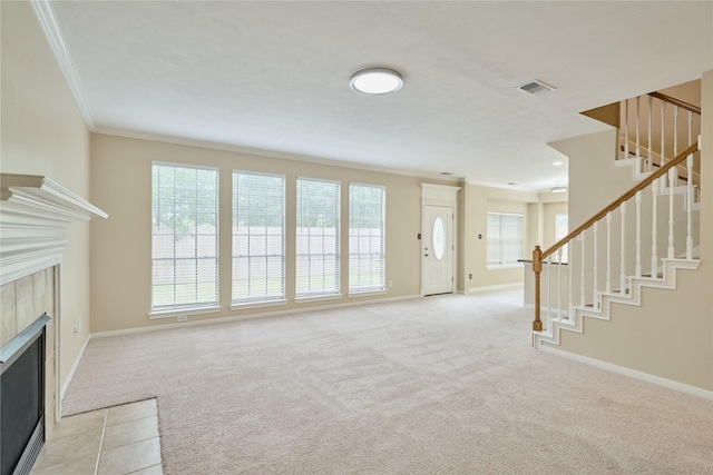 unfurnished living room featuring light colored carpet, crown molding, a healthy amount of sunlight, and a tiled fireplace