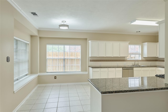 kitchen featuring white cabinets, stainless steel dishwasher, a wealth of natural light, and crown molding