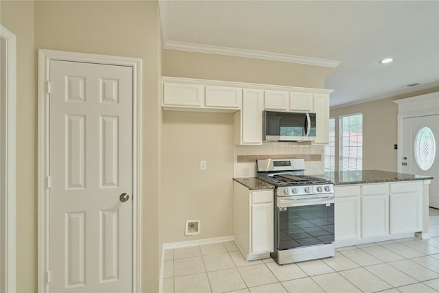 kitchen with light tile patterned floors, backsplash, dark stone countertops, white cabinets, and appliances with stainless steel finishes