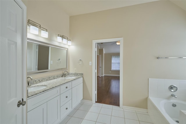 bathroom featuring hardwood / wood-style floors, vanity, vaulted ceiling, and a bathing tub