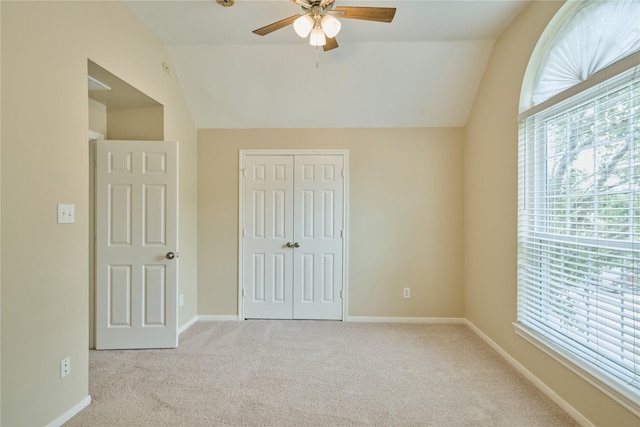 unfurnished bedroom with a closet, light colored carpet, vaulted ceiling, and ceiling fan