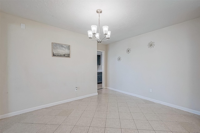 tiled spare room with a textured ceiling and an inviting chandelier