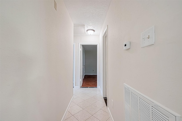 hall featuring light tile patterned flooring and a textured ceiling