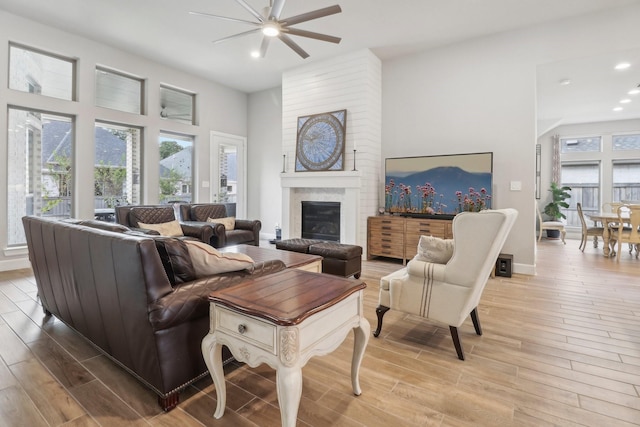 living room with ceiling fan, a fireplace, and light wood-type flooring