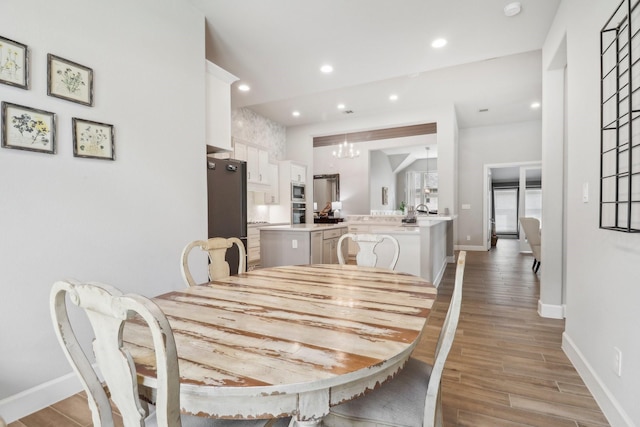 dining space with light wood-type flooring and an inviting chandelier