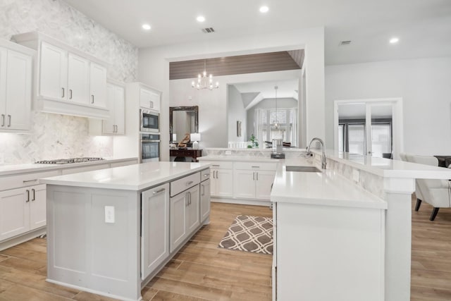 kitchen featuring white cabinetry, kitchen peninsula, stainless steel appliances, and an inviting chandelier