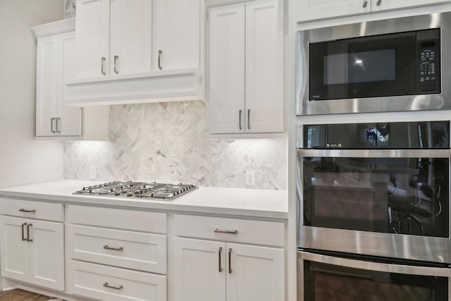 kitchen with white cabinets, decorative backsplash, wood-type flooring, and appliances with stainless steel finishes