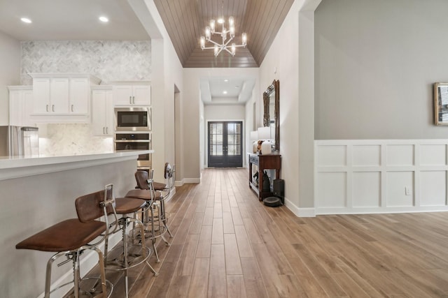 kitchen featuring white cabinets, light hardwood / wood-style floors, appliances with stainless steel finishes, and a chandelier