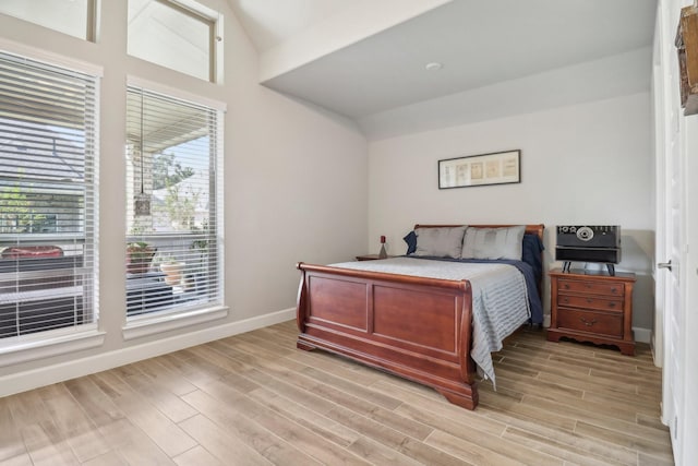 bedroom with light wood-type flooring and lofted ceiling