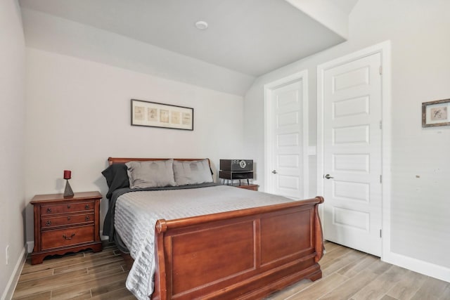 bedroom featuring vaulted ceiling and light wood-type flooring