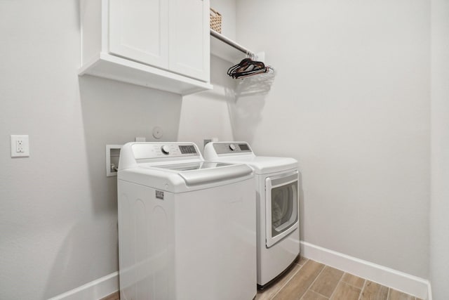 washroom featuring cabinets, light wood-type flooring, and separate washer and dryer