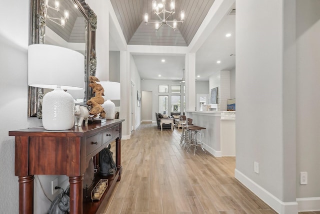 foyer with ceiling fan with notable chandelier, light hardwood / wood-style floors, a tray ceiling, and wood ceiling