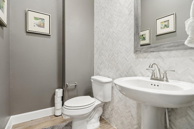 bathroom featuring wood-type flooring, tile walls, and toilet